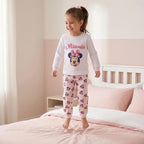 Meisje op bed in de wit met lichtroze Minnie Mouse pyjama