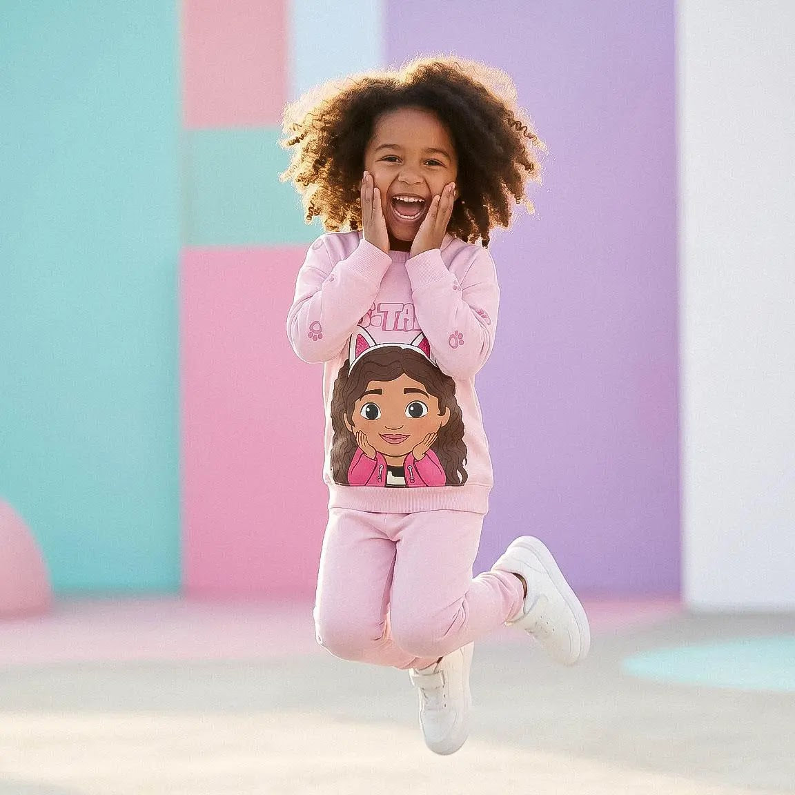 Springend meisje in de lichtroze Gabby sweater