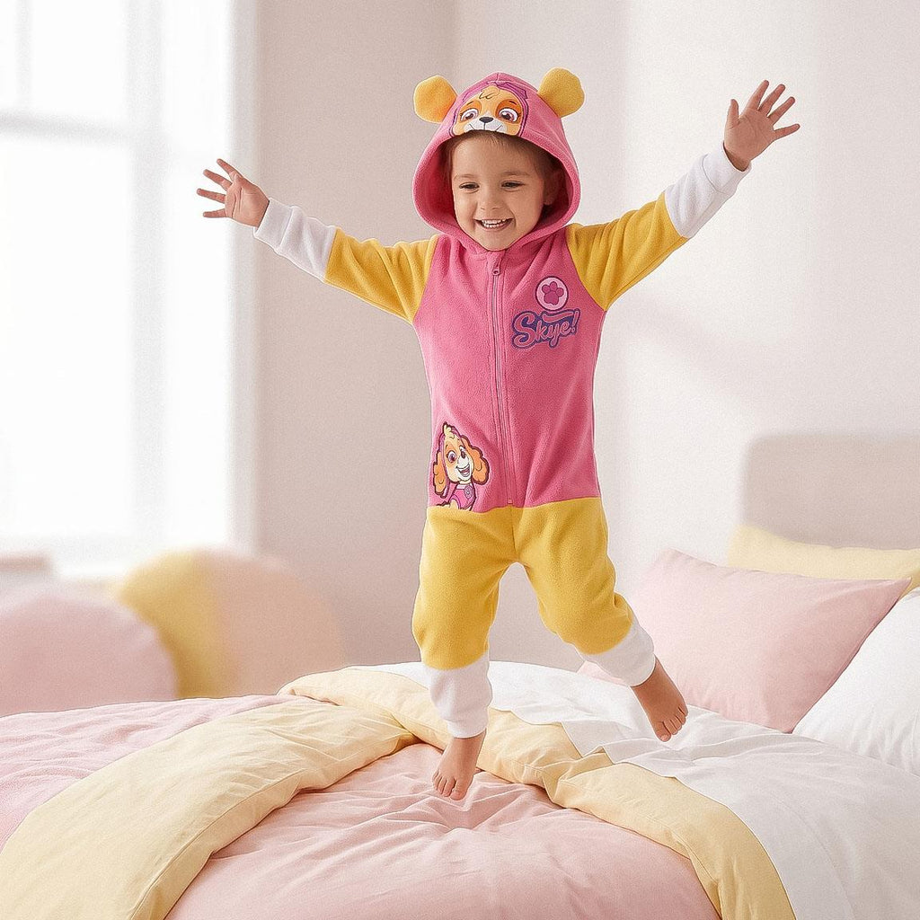 Meisje in Paw Patrol Skye onesie springt vrolijk op bed