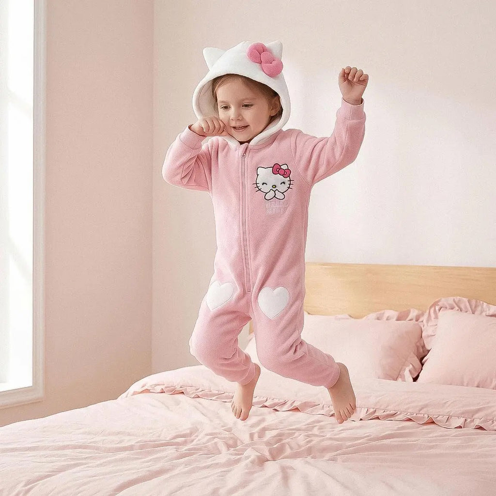 Meisje in Hello Kitty onesie springt op een roze bed