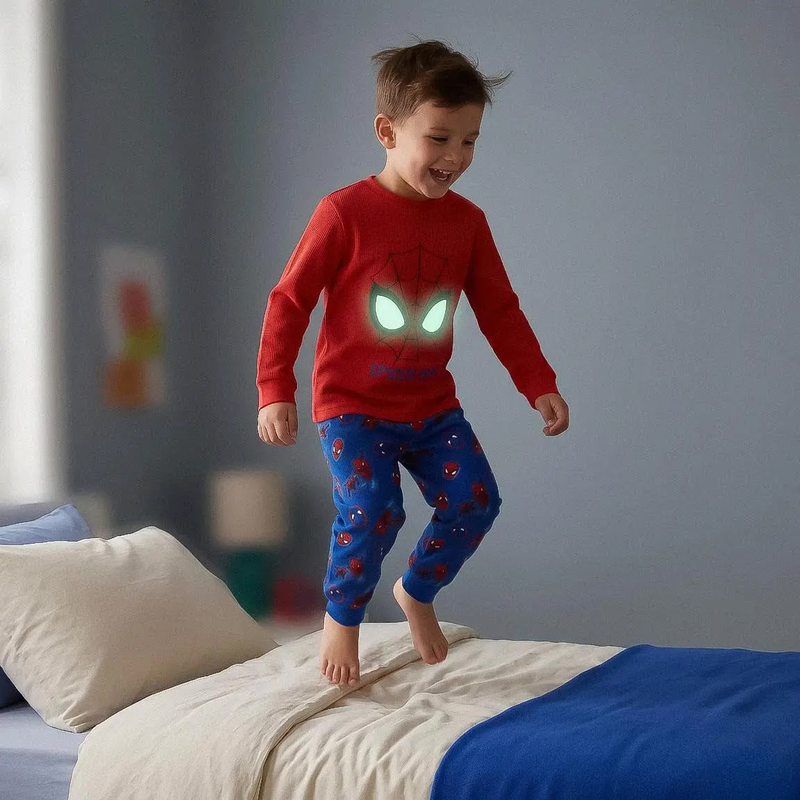Jongen op bed met oplichtende Spiderman ogen in het donker
