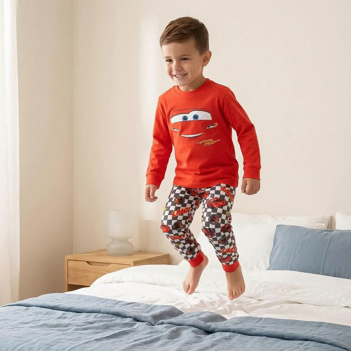 Jongen springt op bed in de rode Lightning McQueen pyjama